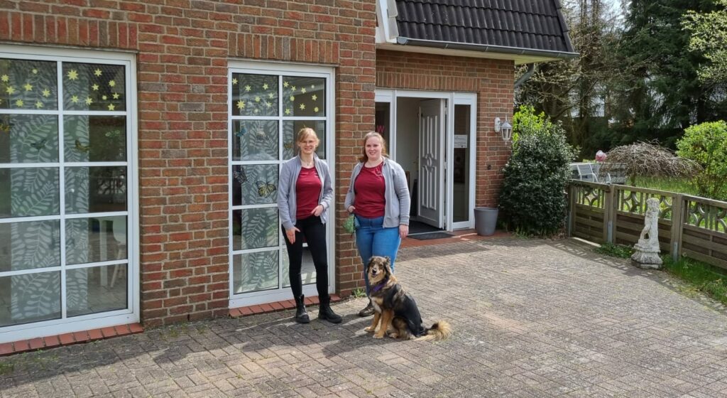 Das sind wir: Annabell Deitlaff und Hanna Schröder mit dem Therapiehund Smilla vor unser Praxis für Ergotherapie im Gleisdreieck in Lübeck